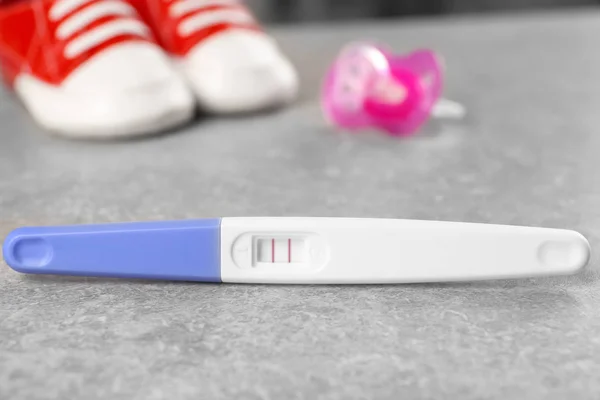 Pregnancy test and baby shoes — Stock Photo, Image