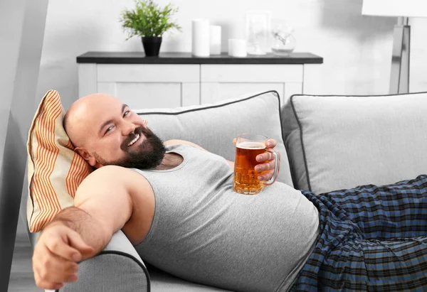 Man met glas bier op zijn grote buik thuis — Stockfoto