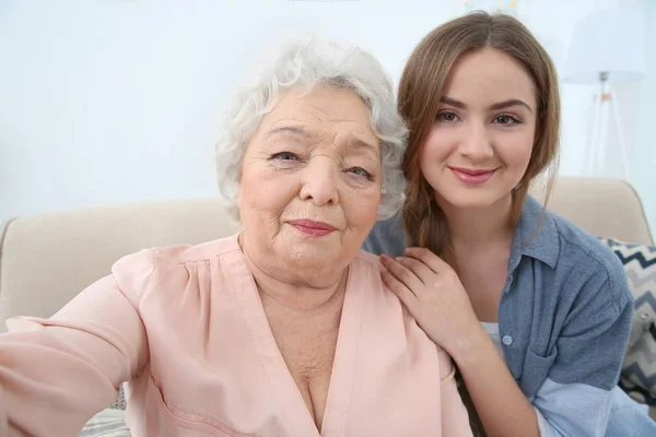 Девочка с бабушкой делают селфи на диване у себя дома — стоковое фото
