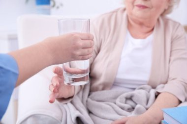 Yaşlı kadına su veren hemşire