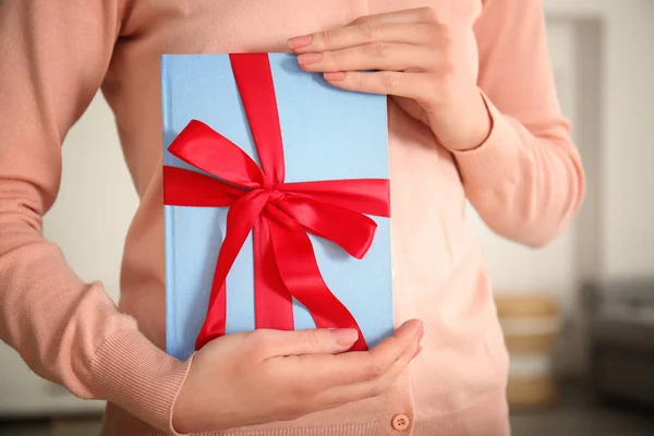 Mujer sosteniendo libro con cinta como regalo — Foto de Stock