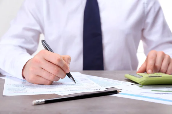 Homme travaillant avec des documents et une calculatrice — Photo