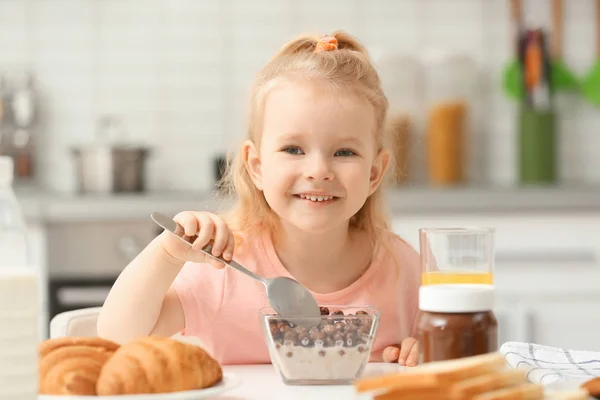 Söt liten flicka äter frukost hemma — Stockfoto