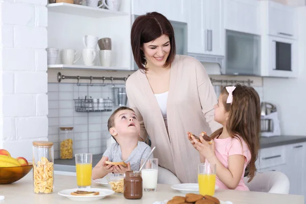 Mãe e crianças tomando café da manhã em casa — Fotografia de Stock
