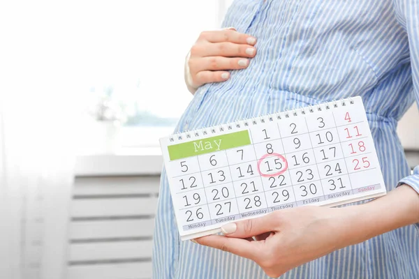 Mulher grávida segurando calendário — Fotografia de Stock