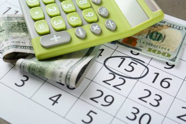 Yeşil hesap makinası ve takvim üzerinde para