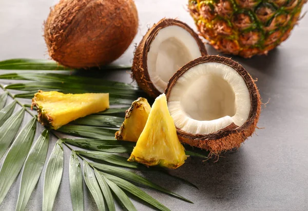 Ananas und Kokosnuss auf grauem Hintergrund — Stockfoto