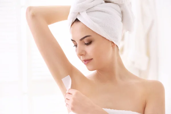 Young woman removing armpit hair