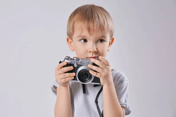 Roztomilý chlapec s fotoaparátem na světlé pozadí — Stock fotografie