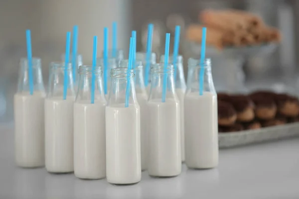 Bottles with milk and straws on table — Stock Photo, Image