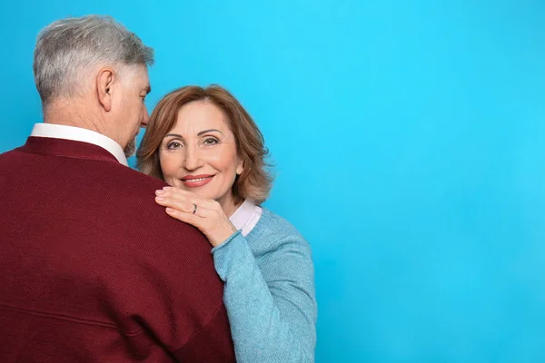 Lycklig senior kvinna omfamnar hennes make på färgbakgrund — Stockfoto