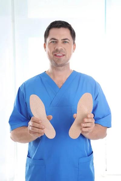 Male orthopedist with insoles on white background — Stock Photo, Image