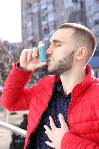 Человек, использующий ингалятор астмы
