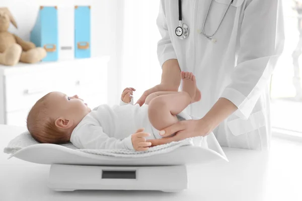 Kvinnelig lege som veier et søtt barn på klinikken – stockfoto