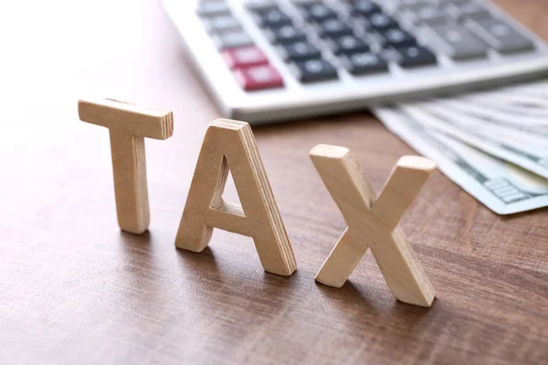 Wooden word "TAX" and calculator — Stock Photo, Image