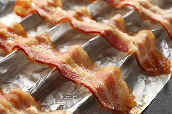 Tiras de bacon frito em papel alumínio — Fotografia de Stock