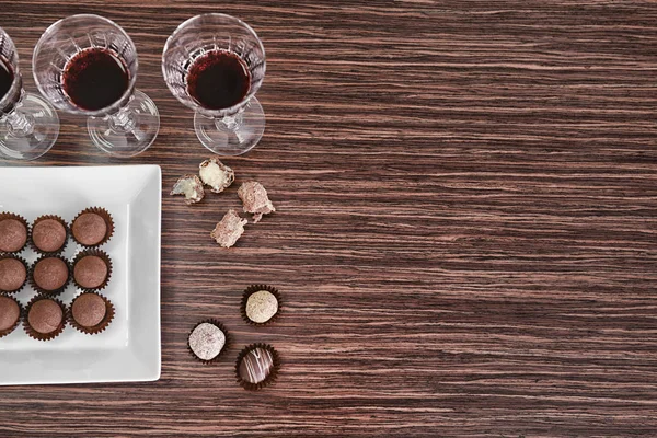 Red wine and chocolates on wooden background — Stock Photo, Image