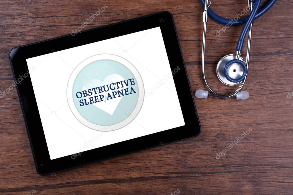 Tablet with stethoscope on wooden background