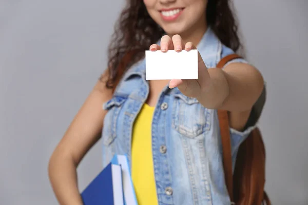 灰色の背景は、クローズ アップのビジネス カードを使って女子学生 — ストック写真