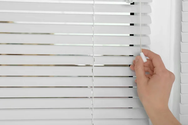 Kvinnlig hand öppna vita persienner på fönster, närbild — Stockfoto