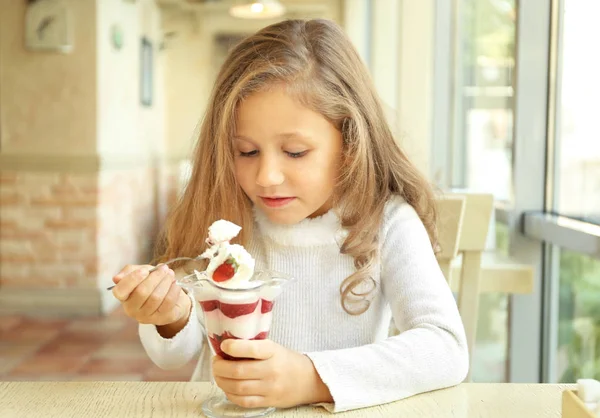 Vicces kis lány eszik fagylaltot, kávézó — Stock Fotó