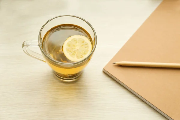 Cup of hot tea, notebook and pencil — Stock Photo, Image