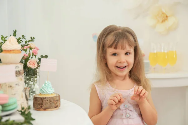 Симпатична дівчина біля столу з цукерками, поданими на вечірку — стокове фото