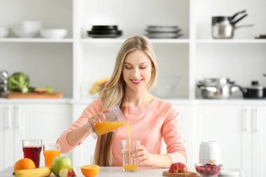 Güzel genç kadın mutfakta taze meyve suyu hazırlama