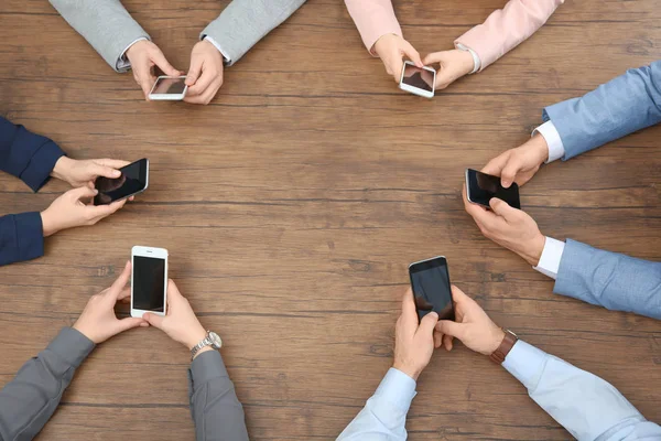 People sitting at table and using smartphones