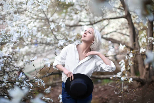 Jonge vrouw in de buurt van bloeiende Magnoliaboom — Stockfoto