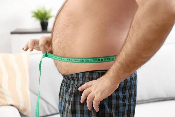 Hombre midiendo barriga de cerveza en casa —  Fotos de Stock