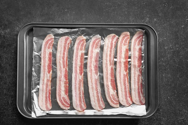 Baking tray with strips of bacon — Stock Photo, Image