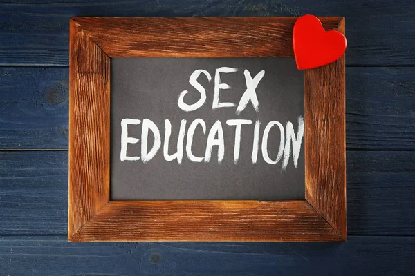 Небольшая доска с текстом SEX EDUCATION на деревянном фоне — стоковое фото