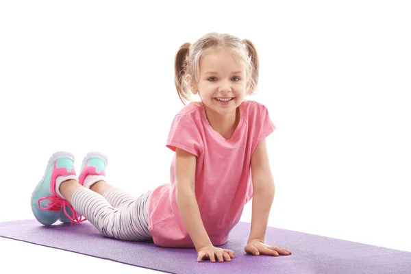 Schattig meisje doet gymnastische oefeningen op mat, geïsoleerd op wit — Stockfoto