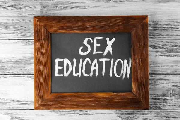 Small blackboard with text SEX EDUCATION on wooden background — Stock Photo, Image
