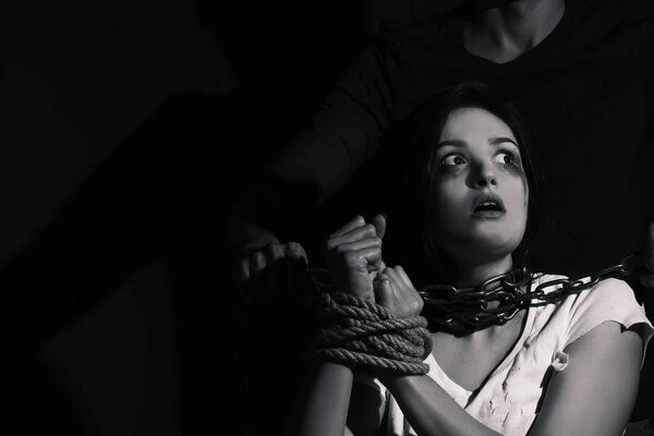 Young woman with tied hands subjected to violence in darkness