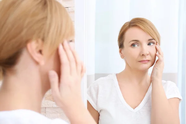 Happy senior woman applying cream — Stock Photo, Image