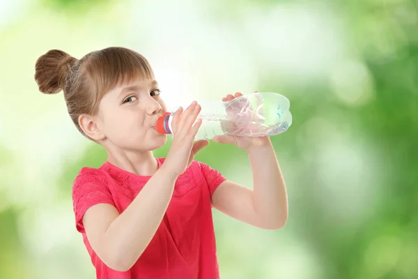 Маленькая девочка с бутылкой чистой воды на размытом фоне — стоковое фото