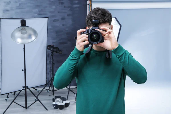 Jovem fotógrafo profissional com câmera em estúdio — Fotografia de Stock