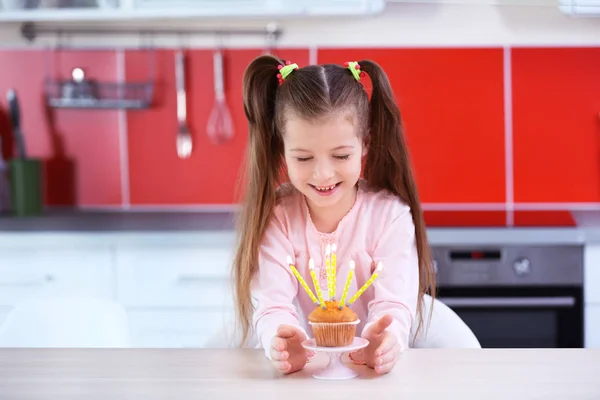 Cute little girl with birthday cake in kitchen