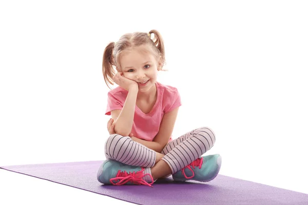 Милая девушка делает гимнастические упражнения на коврике, изолированные на белом — стоковое фото