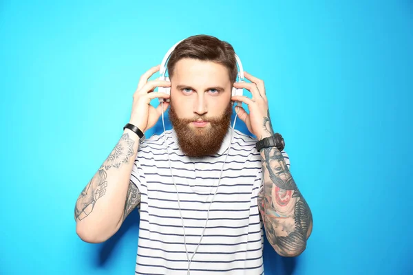 Joven barbudo escuchando música con auriculares sobre fondo azul — Foto de Stock