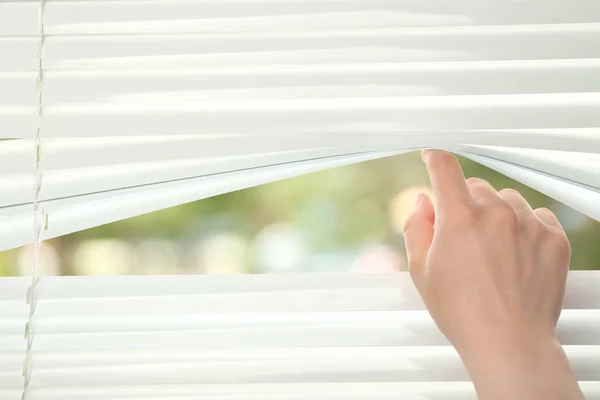 Female hand separating slats of blinds — Stock Photo, Image