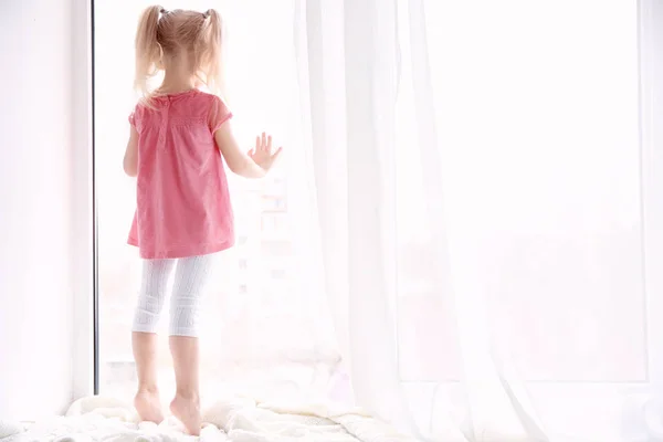 Little girl standing on windowsill — Stock Photo, Image