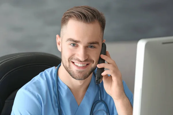 Young medical assistant talking by telephone while working in office