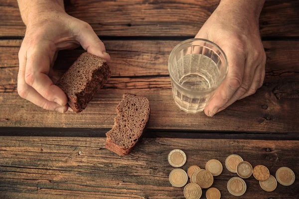 Hands with glass of water, bread and coins — Stock Photo, Image