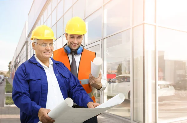 Equipe de engenheiros com desenhos de projetos perto do edifício moderno — Fotografia de Stock