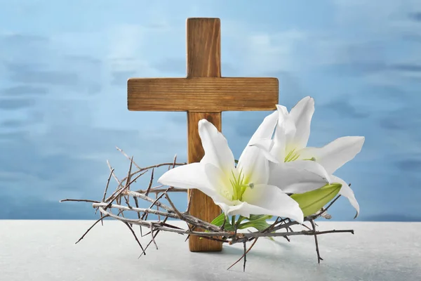 Crown of thorns, wooden cross and white lily on table — Stock Photo, Image