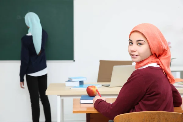 Gadis lucu duduk di meja di kelas sekolah — Stok Foto