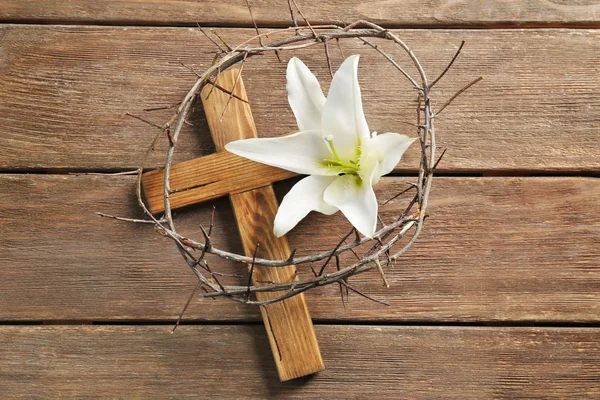 Corona de espinas, cruz de madera y lirio blanco sobre la mesa — Foto de Stock